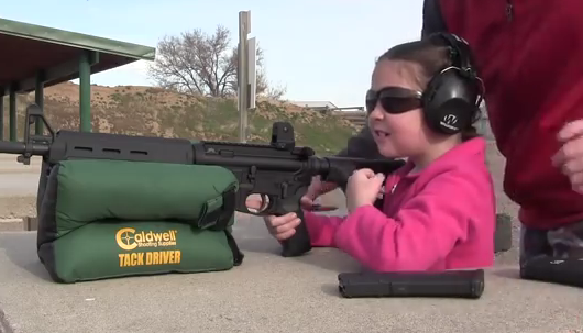 Young girl shooting with adult guidance